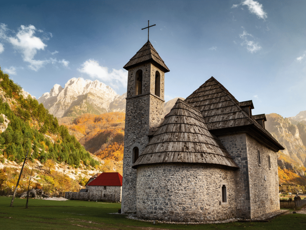 The historic stone Catholic church of Theth village with Albanian Alps peaks in the background